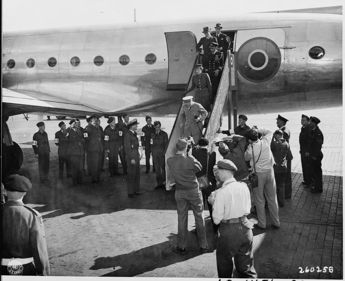 Prime Minister Winston Churchill, surrounded by cameramen and dignitaries, leaves the airplane which brought him to... - NARA - 198870