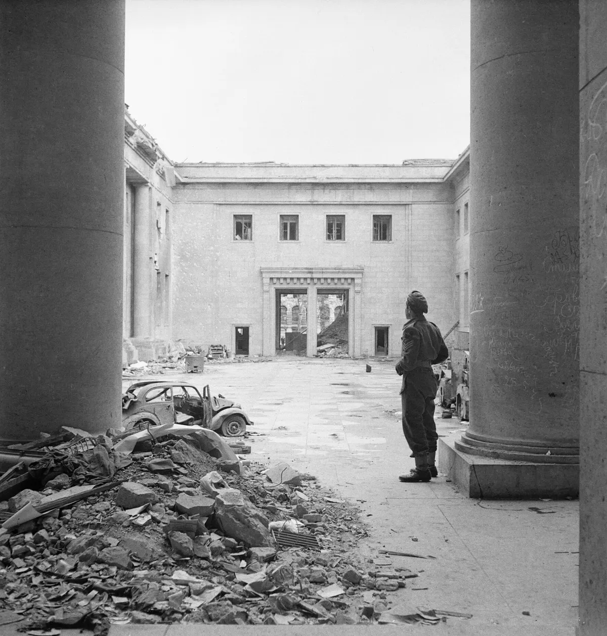Sergeant R S Baker of the Army Film and Photograph Unit standing in the courtyard of the ruined Chancellery building in Berlin, 2 July 1945. BU8569